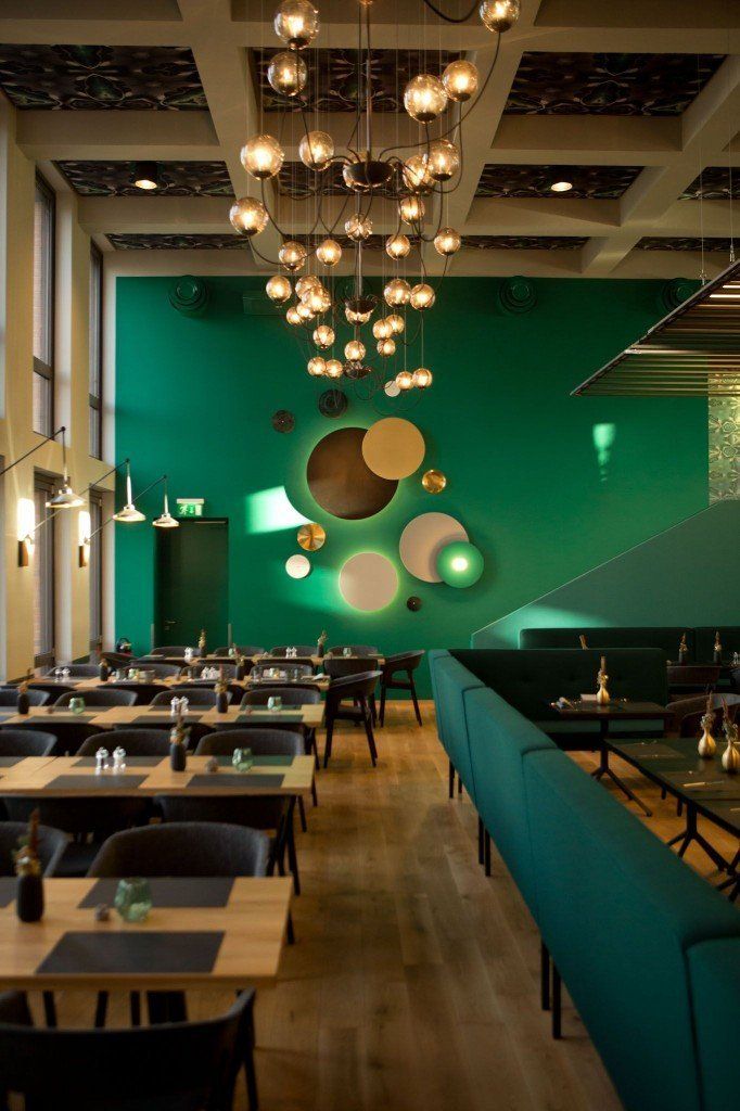 Ein Restaurant mit Tischen und Stühlen und einer grünen Wand.