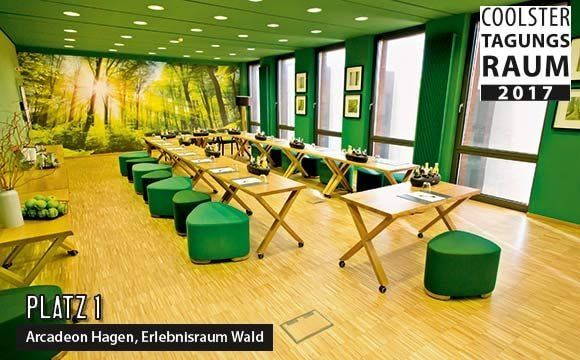 Ein Raum mit grünen Tischen und grünen Ottomanen und einem Schild mit der Aufschrift „Coolster Tagungsraum 2017“