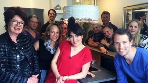 Eine Gruppe von Menschen posiert in einem Raum für ein Foto.