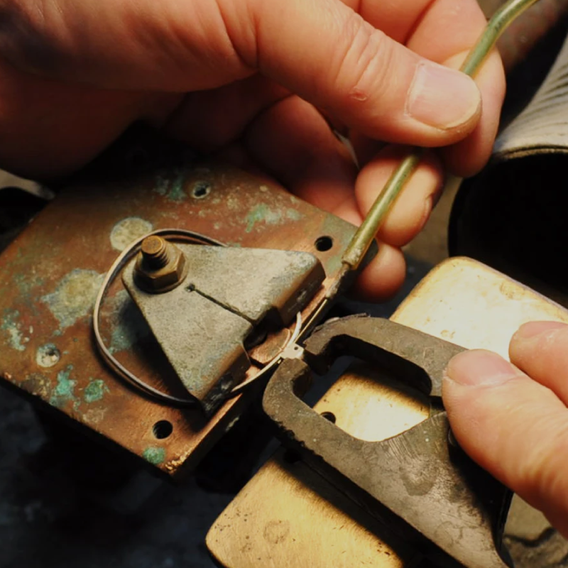 Artisan using a small tool to craft a piece for eyeglass frame