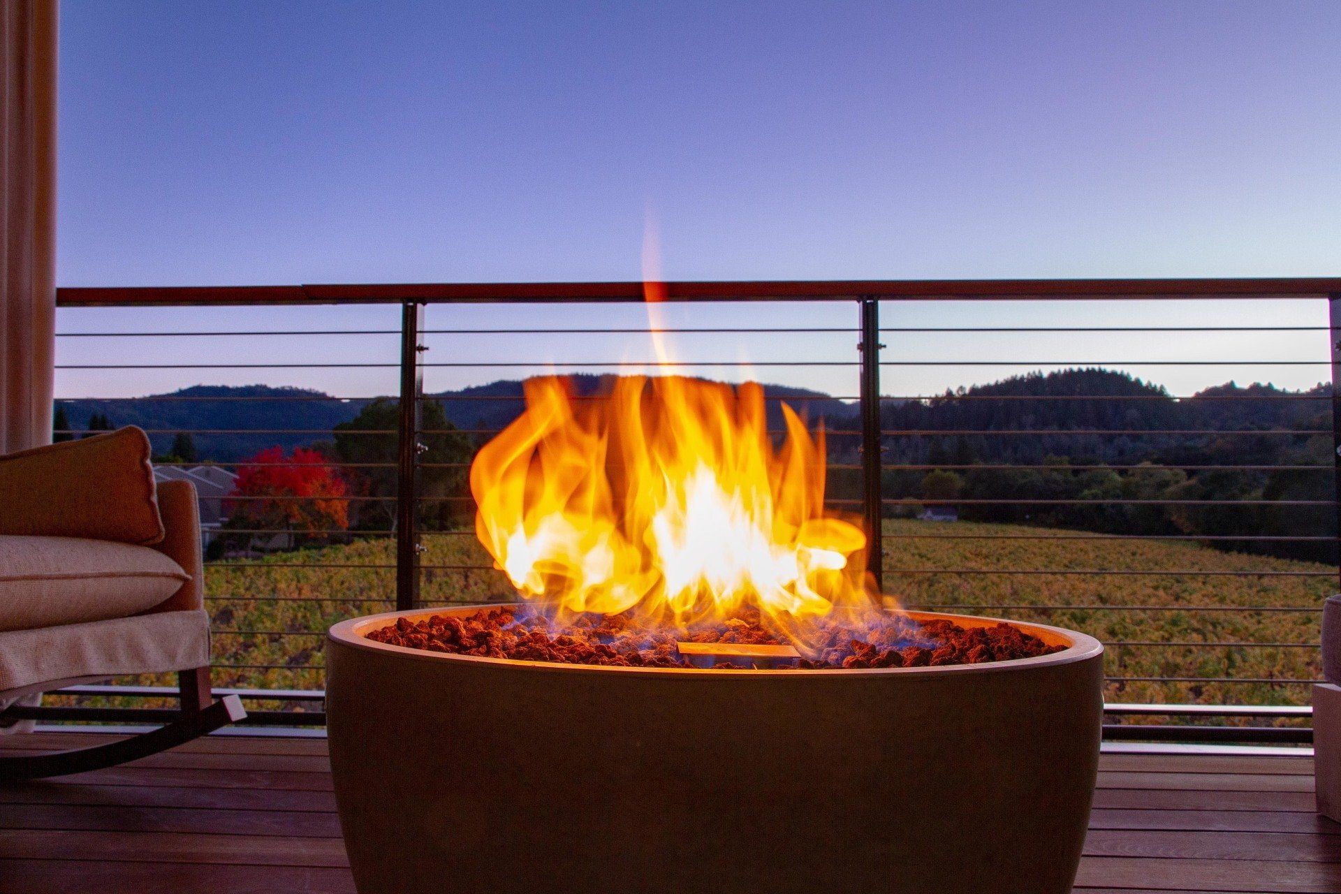 A fire pit on a deck with a view of a field.