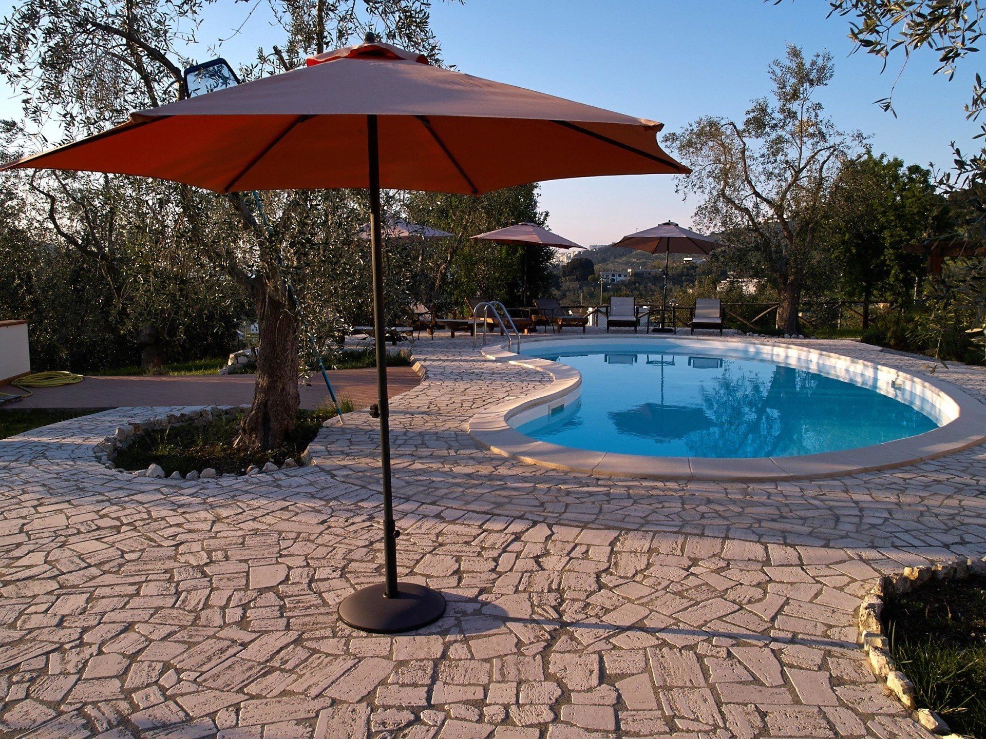 An orange umbrella is sitting in front of a swimming pool