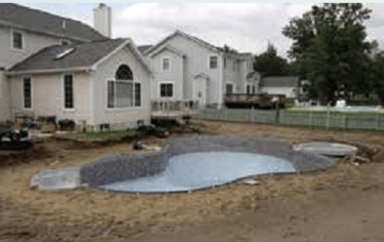 A swimming pool is being built in the backyard of a house.