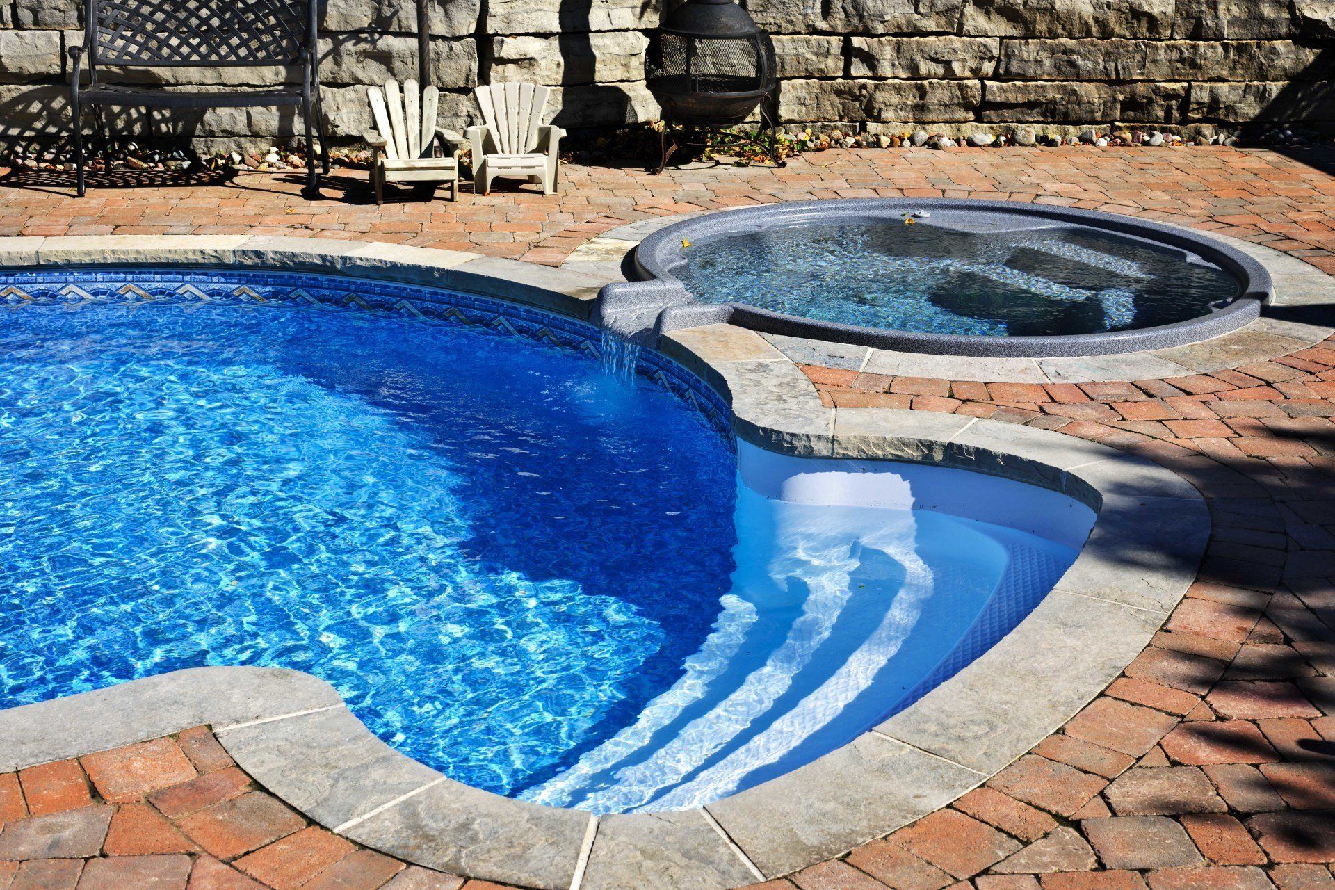 A large swimming pool with a hot tub next to it