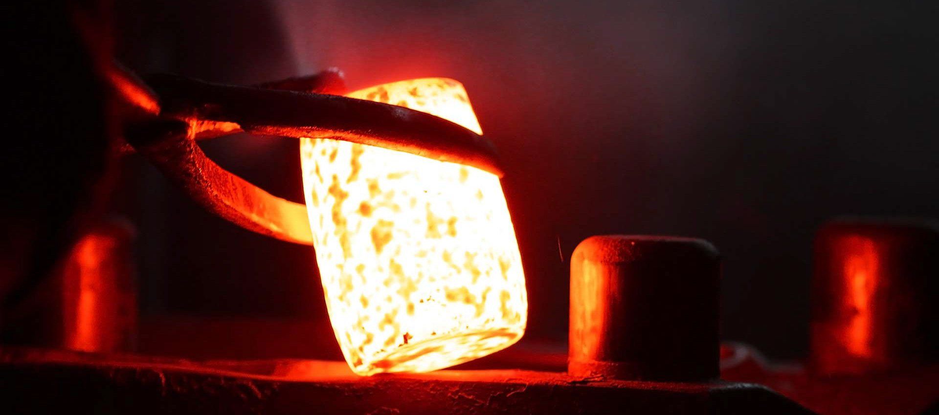 Ein Stück heißes Metall wird in einen Ofen gegossen.