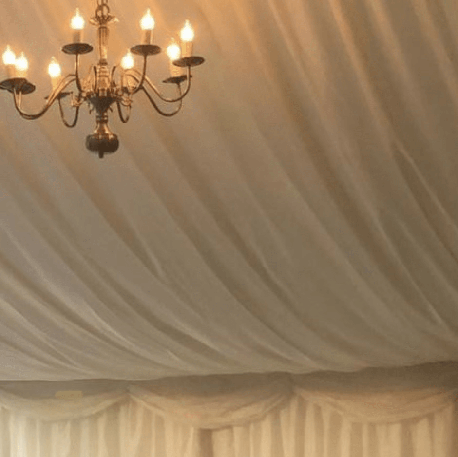 Chandelier hangs from a draped, ivory-colored fabric ceiling.