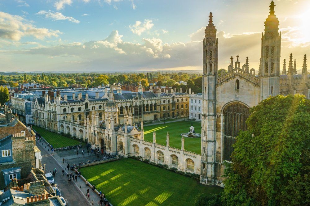 Marquee Hire Cambridge Aerial view of King's College, Cambridge, with a green lawn, stone buildings, and a sunny sky.