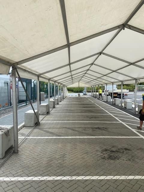 Covered parking lot with concrete barriers. White canopy. Empty parking spaces.