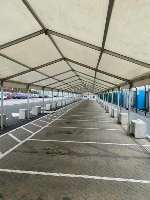 Covered parking lot with empty spaces, white roof, concrete barriers, and painted parking lines.