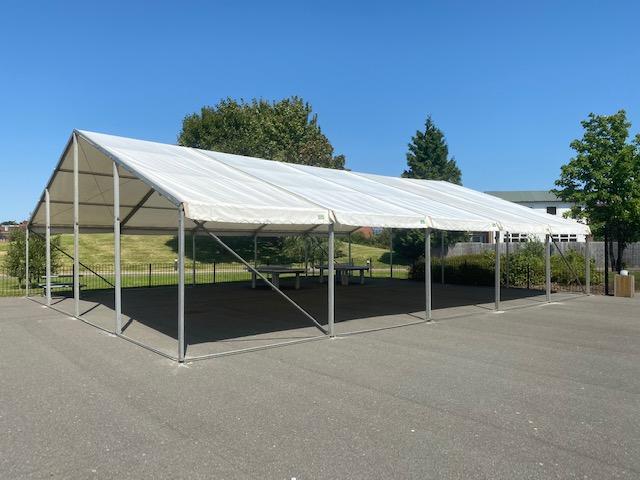 White tent set up on asphalt, sunny outdoor scene.