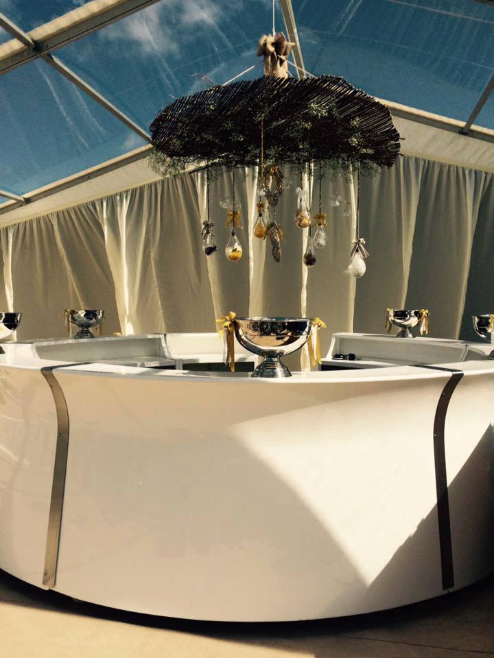 White buffet table set under tent with decorative hanging elements.