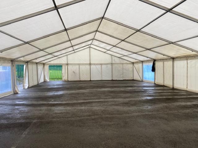 Interior of a large white event tent with a concrete floor.