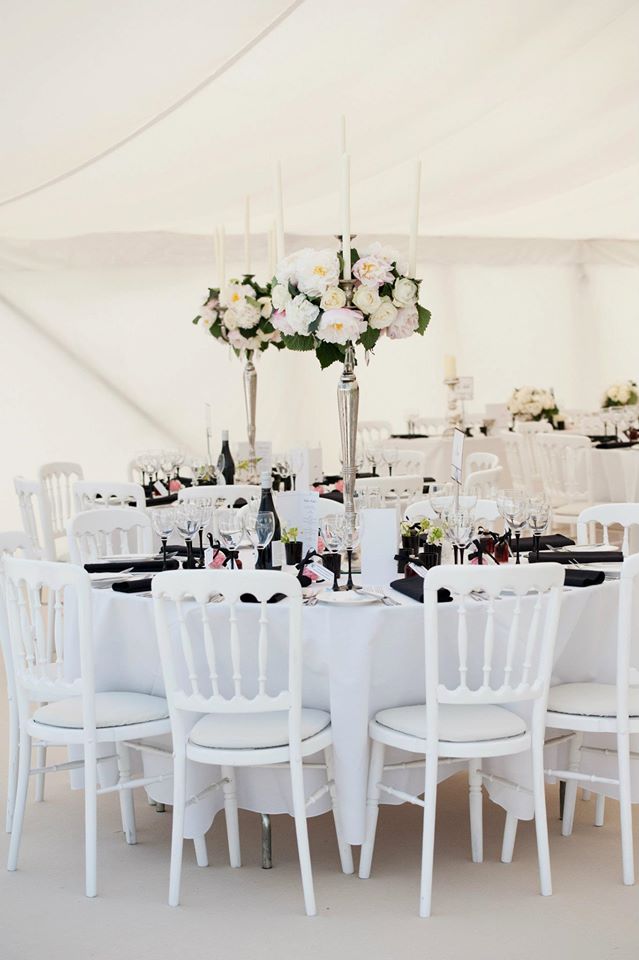 Round tables set for a formal event, with white linens, chairs, and floral centerpieces.