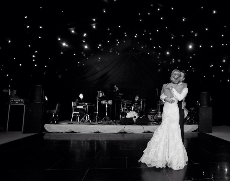 Couple dancing on a black dance floor, band on stage, star-lit ceiling.
