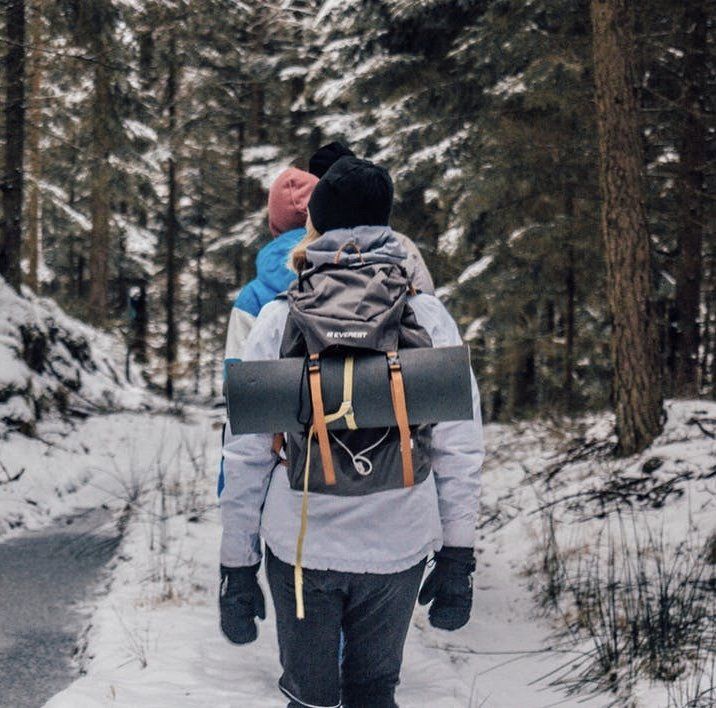 2 people walking in a snowy forest carrying backpacks