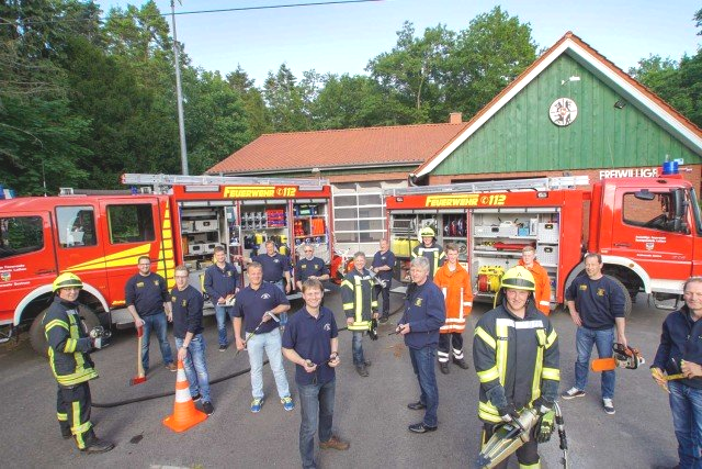 Eine Gruppe von Feuerwehrleuten steht vor einem grünen Gebäude