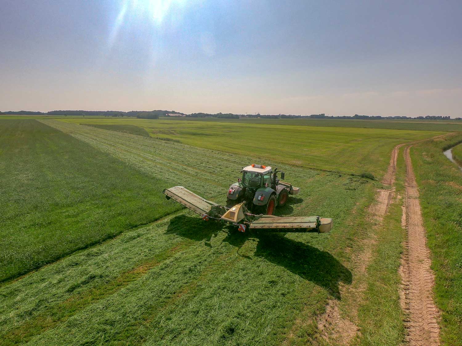 Eine Luftaufnahme eines Traktors, der auf einem Feld Gras schneidet.