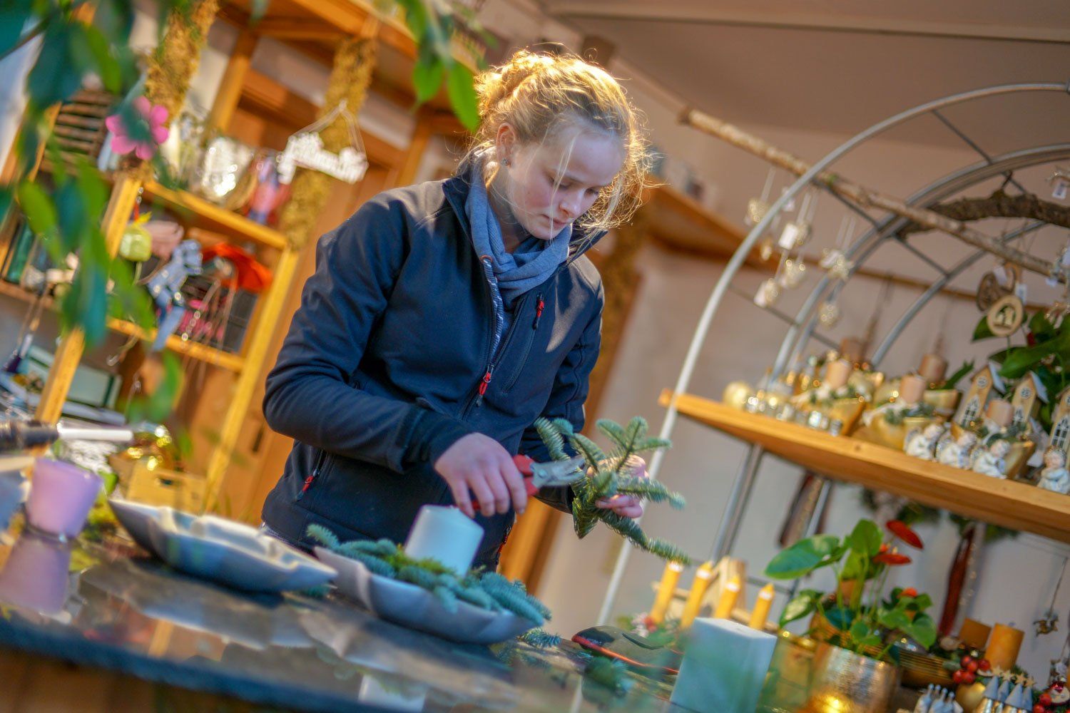 Eine Frau schneidet Blumen auf einem Tisch in einem Zimmer.