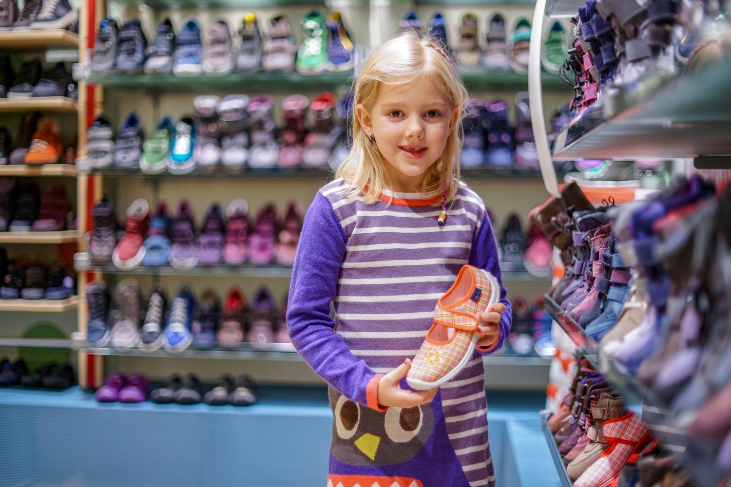 Ein kleines Mädchen hält in einem Schuhgeschäft einen Schuh.