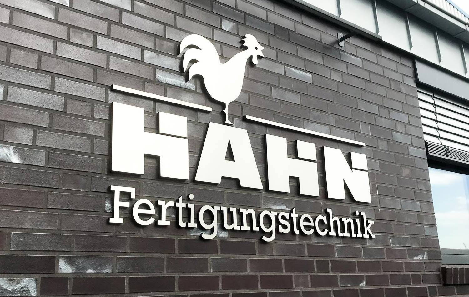 A sign on a brick wall that says hahn fertigungstechnik