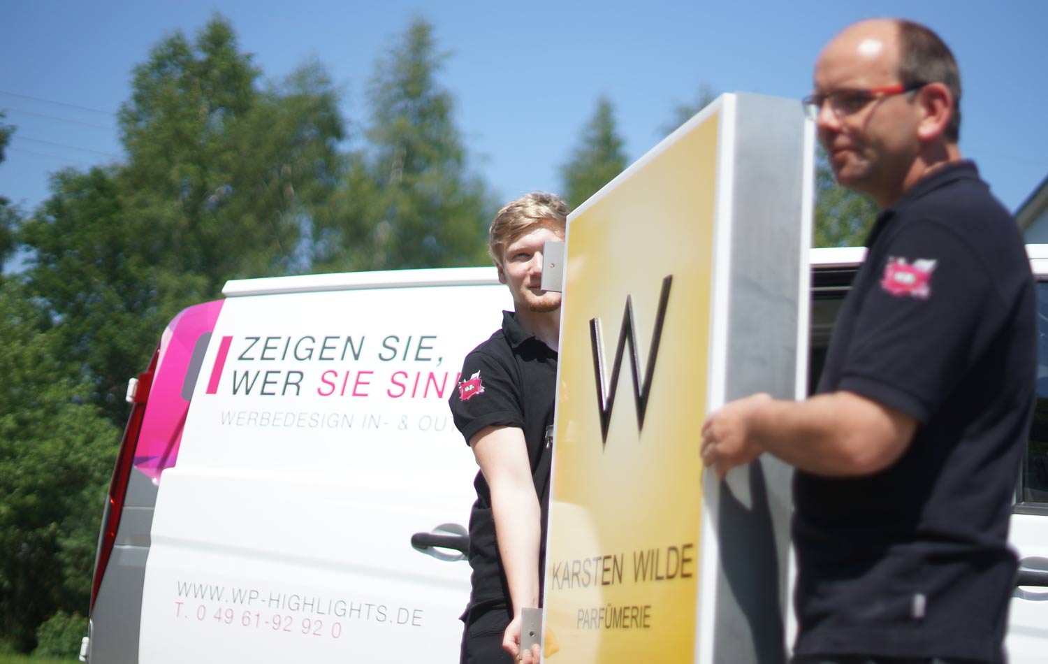 Zwei Männer tragen ein großes Schild mit der Aufschrift 