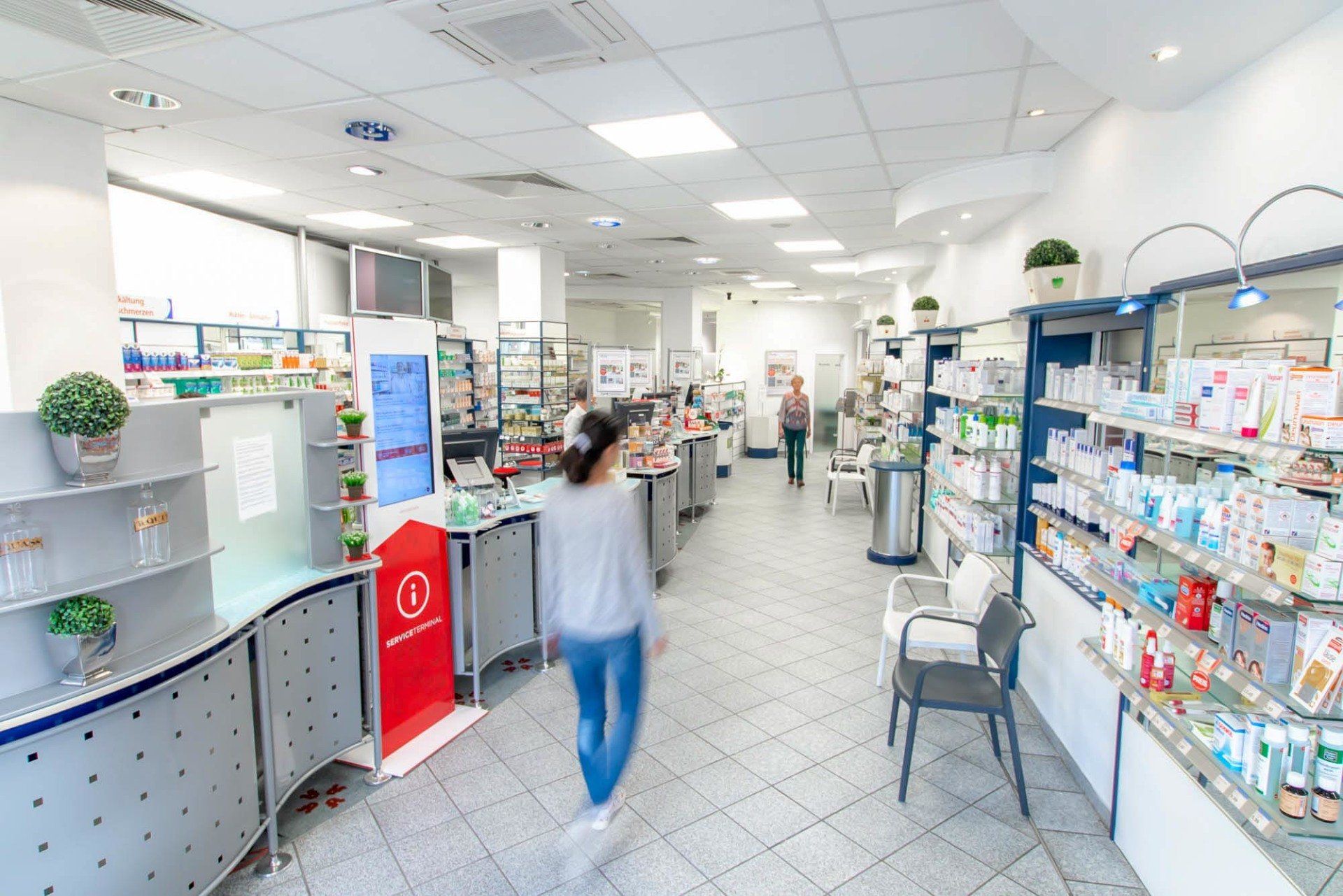 Eine Frau geht durch den Gang einer Apotheke.