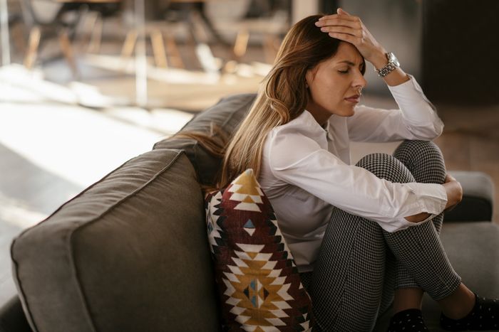 Specialista studiando la giovane seduta sul sofá che se copre la faccia