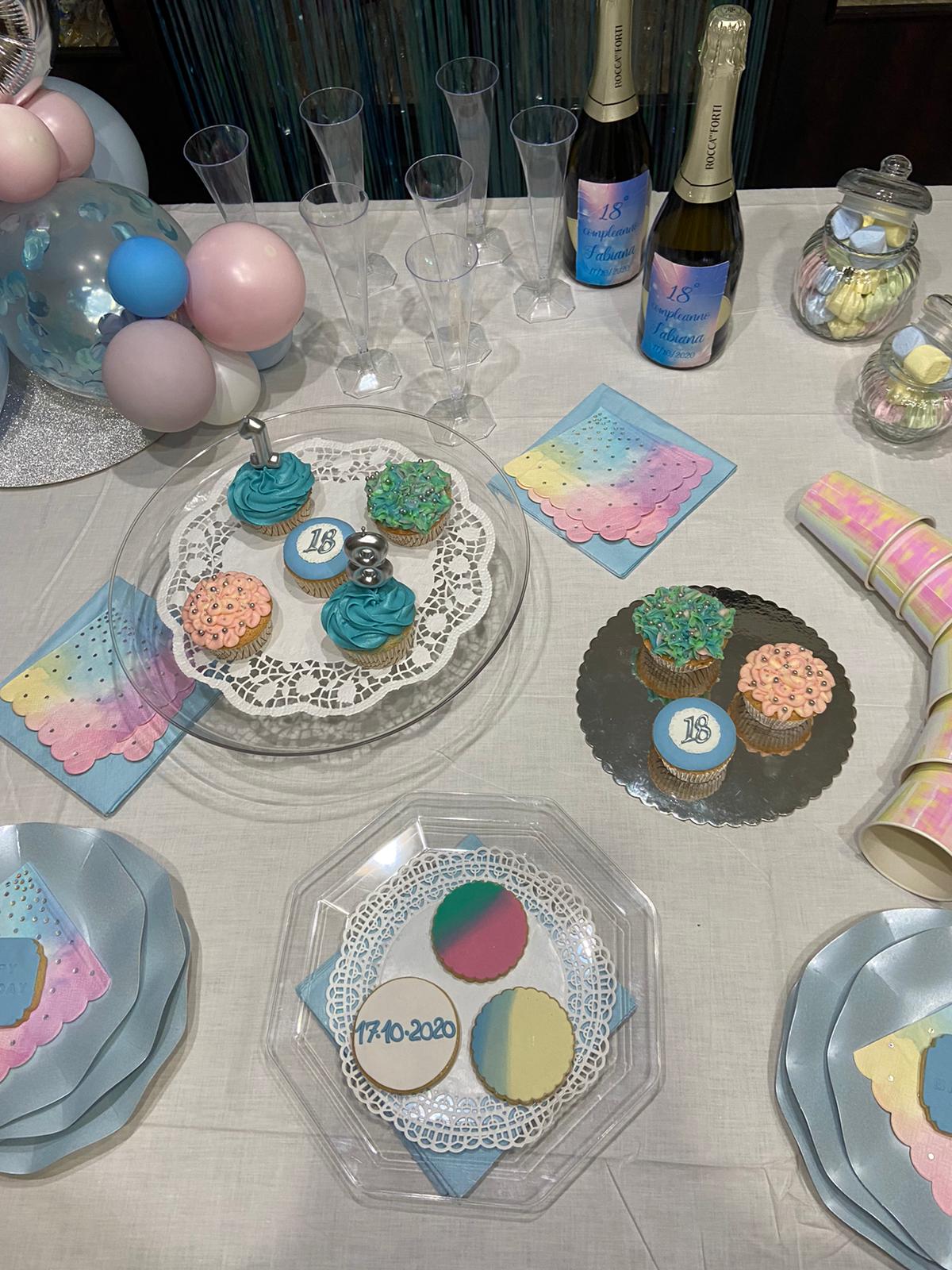 Apparecchiatura per la tavola della festa con cupcake, palloncini, champagne, piatti e decorazioni color pastello.