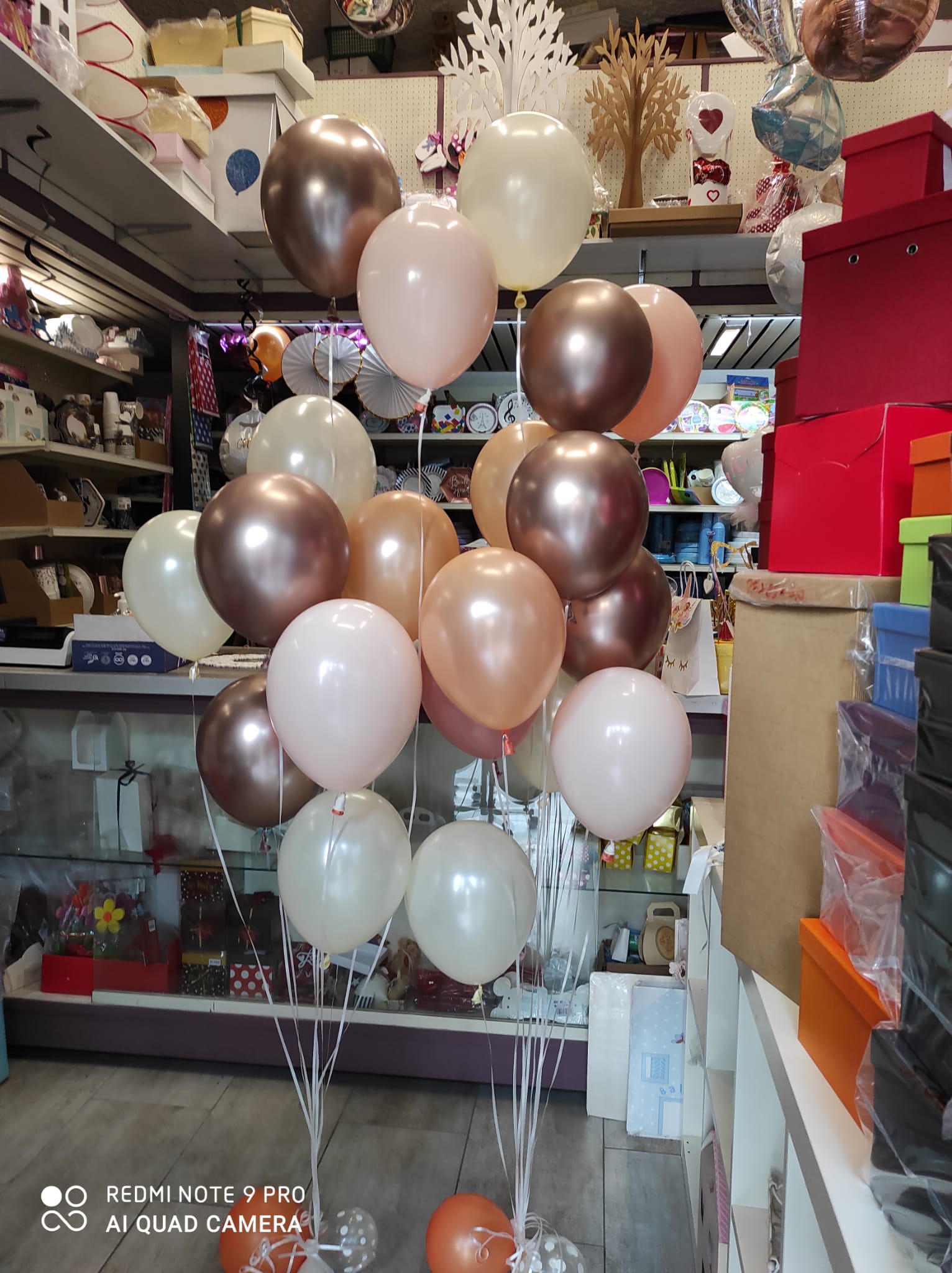 Palloncini nei toni del marrone, pesca e bianco disposti in un negozio.