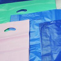 Borse della spesa in plastica colorata, tra cui rosa, verde e blu, con manici fustellati.