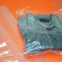 Primo piano di una camicia di jeans piegata in un sacchetto di plastica trasparente. 