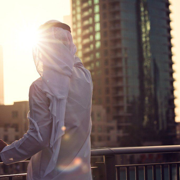 A man in a white shirt is standing on a balcony overlooking a city