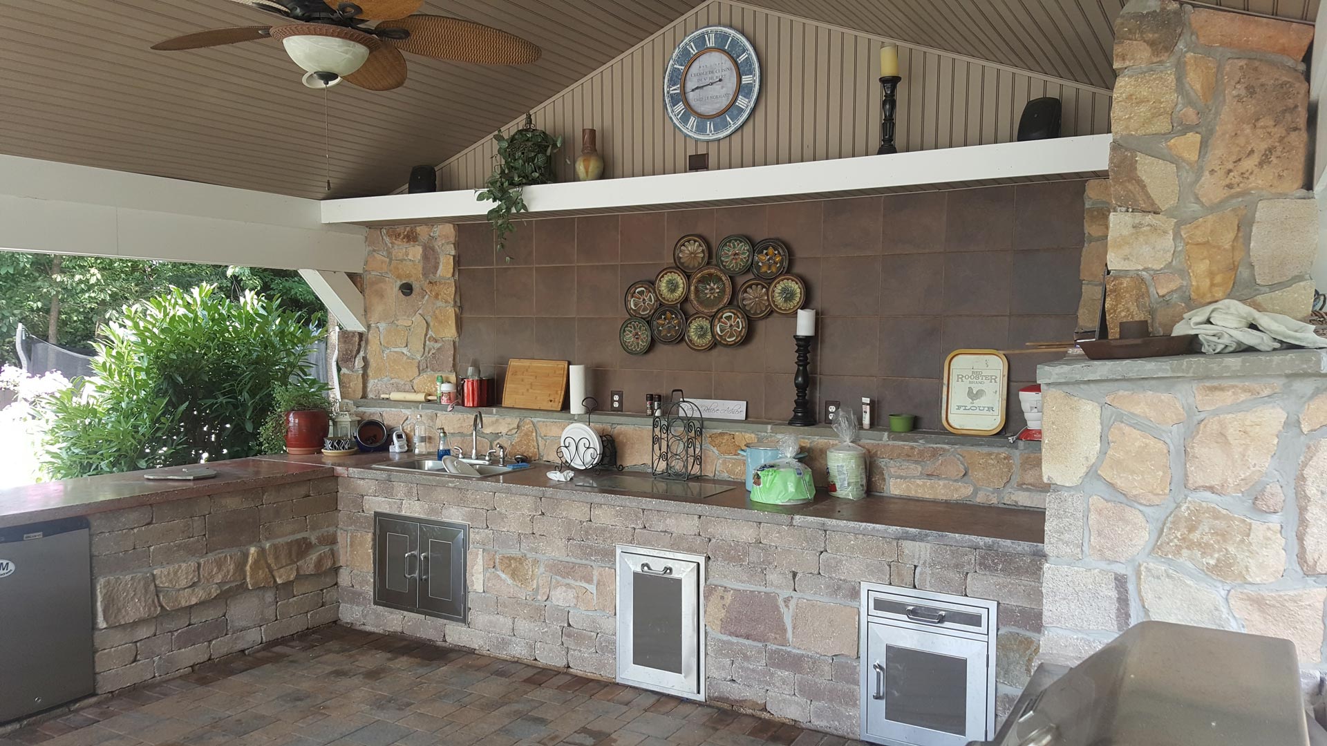 A kitchen with a clock on the wall and a ceiling fan.