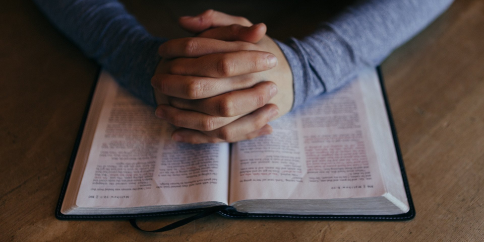 Hands folded on Bible