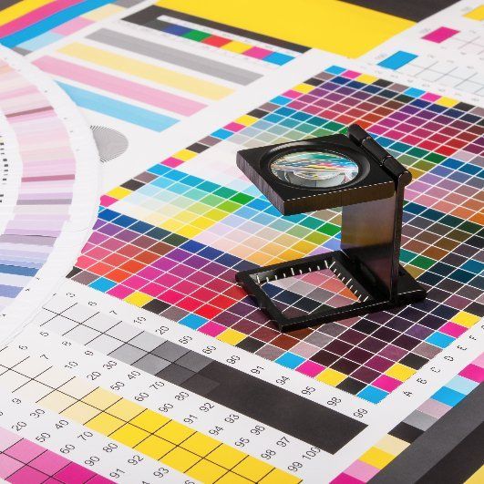 A magnifying glass is sitting on top of a color chart.