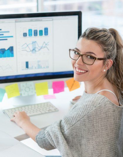 A woman wearing glasses is sitting in front of a computer
