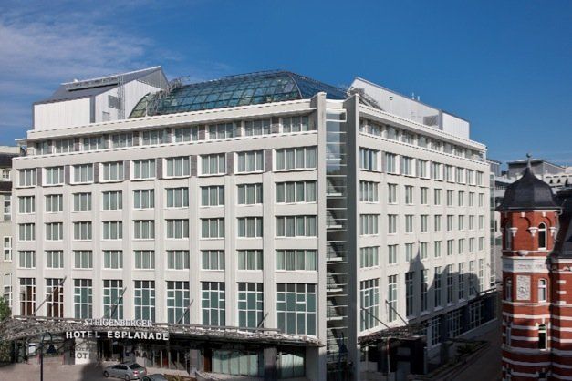 Ein großes weißes Gebäude mit vielen Fenstern an einem sonnigen Tag.