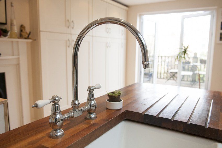 Large silver taps on a wooden kitchen top