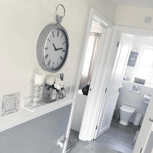 A silver clock on a white wall