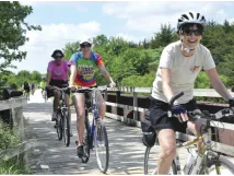A group of people are riding bicycles on a bridge.