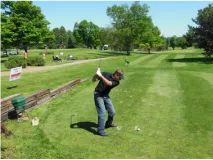 A man is swinging a golf club on a golf course.