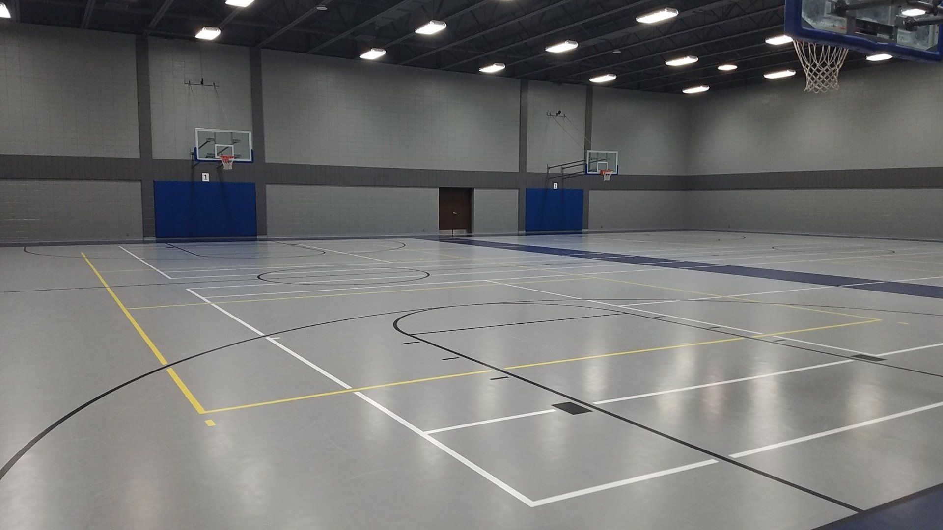 An empty basketball court with a basketball hoop in the background.