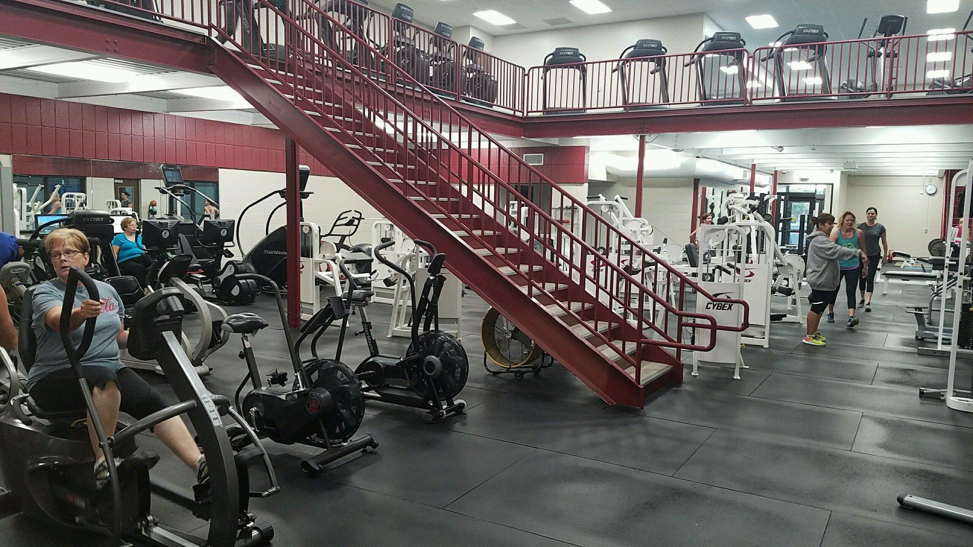 A woman is riding an exercise bike in a gym.