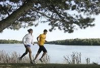 A man and a woman are jogging by a lake.