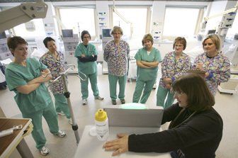 A group of nurses are standing around a woman using a computer
