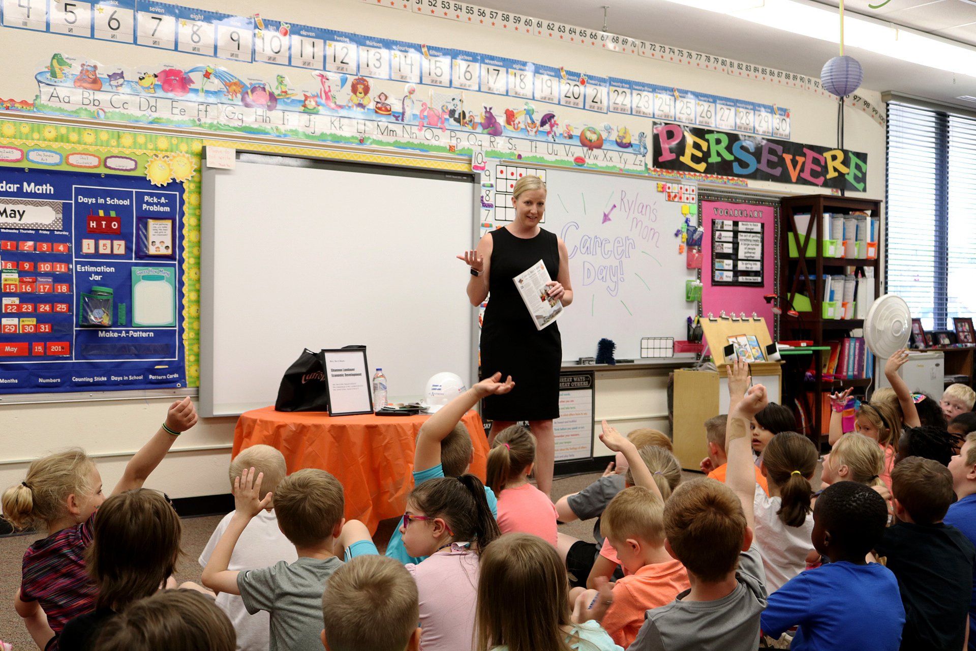A woman is giving a presentation to a group of children in a classroom.