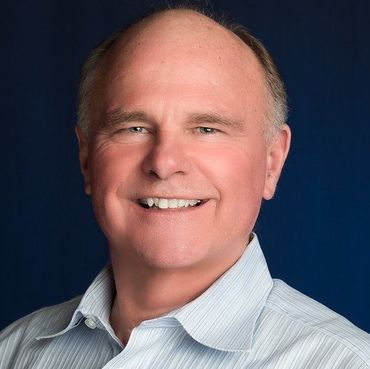 A bald man in a striped shirt is smiling for the camera.