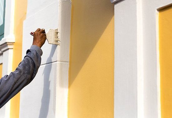 mano di un uomo che dipinge un muro