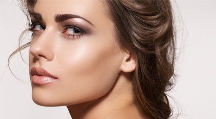 A lady with dewy skin, peach lips and smokey eyes
