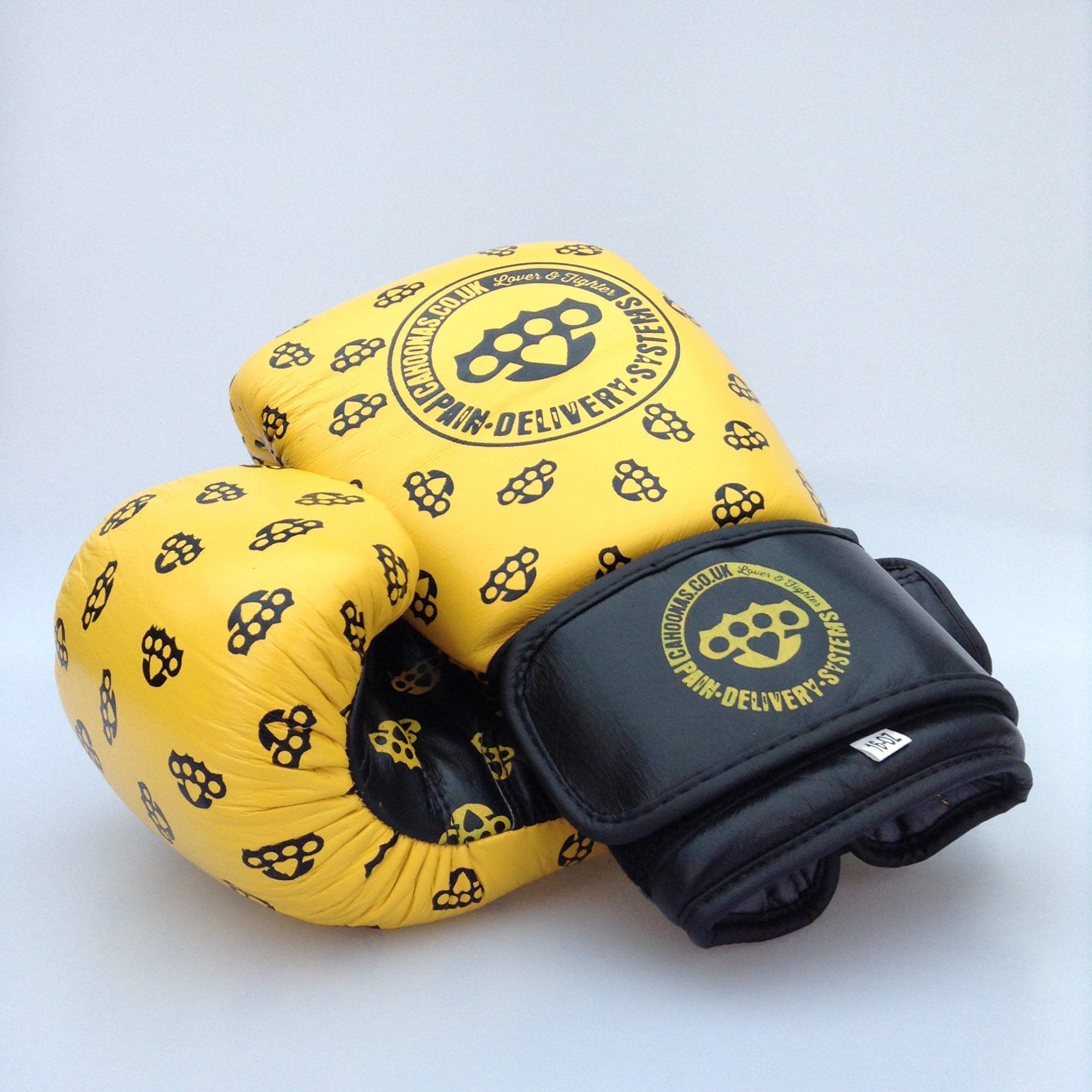 image shows a pair of yellow and black boxing gloves with a knuckleduster repeat pattern on the leather.